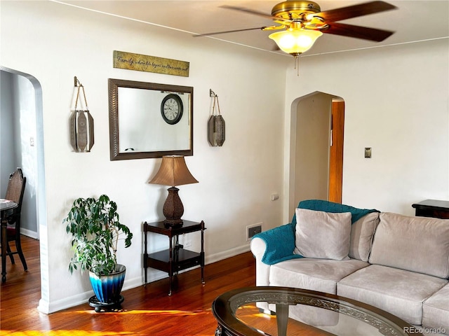 living room with ceiling fan and dark hardwood / wood-style flooring