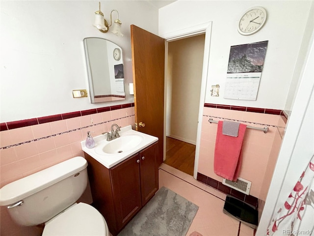 bathroom with tile walls, vanity, and toilet