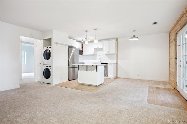 29656 Buffalo Park Rd Unit 208, Evergreen, CO 80439 - kitchen with stacked washing machine and dryer, light colored carpet, appliances with stainless steel finishes, white cabinets, and a kitchen island