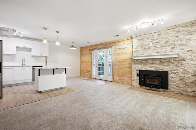 29656 Buffalo Park Rd Unit 208, Evergreen, CO 80439 - unfurnished living room featuring track lighting, wooden walls, light colored carpet, a wood stove, and light wood finished floors