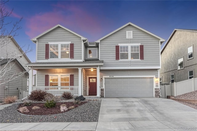 traditional home with covered porch, driveway, fence, and a garage