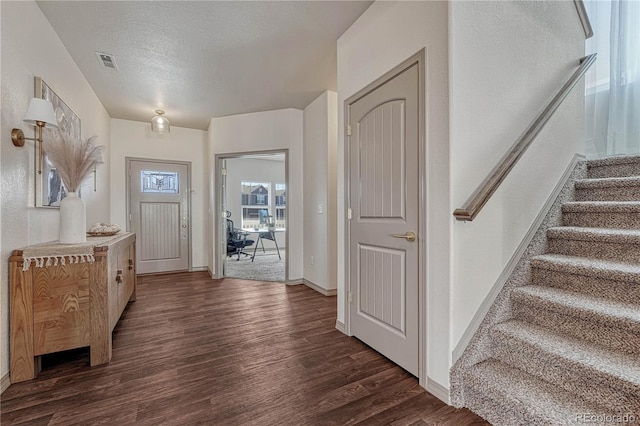 entrance foyer featuring baseboards, visible vents, dark wood-style floors, stairway, and a textured ceiling