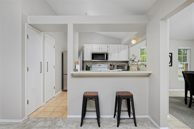 690 W Jamison Cir, Littleton, CO 80120 - kitchen featuring stainless steel microwave, white electric range, freestanding refrigerator, vaulted ceiling, and a kitchen breakfast bar