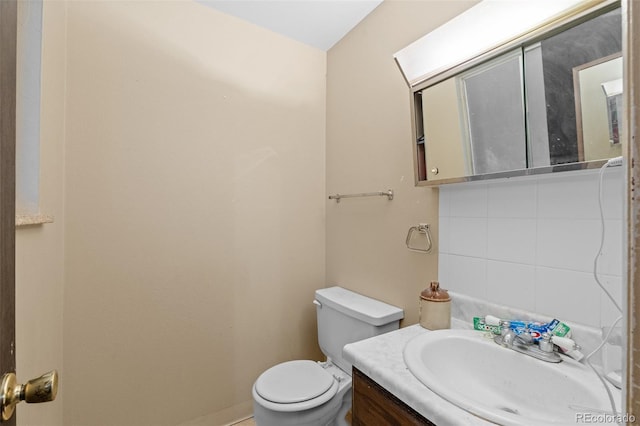 bathroom featuring vanity, toilet, and decorative backsplash