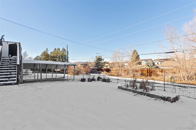 yard layered in snow featuring a carport