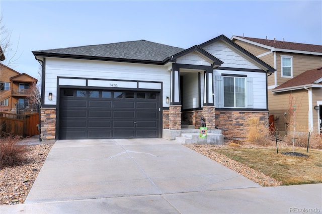 view of front of home featuring fence, an attached garage, a shingled roof, concrete driveway, and stone siding