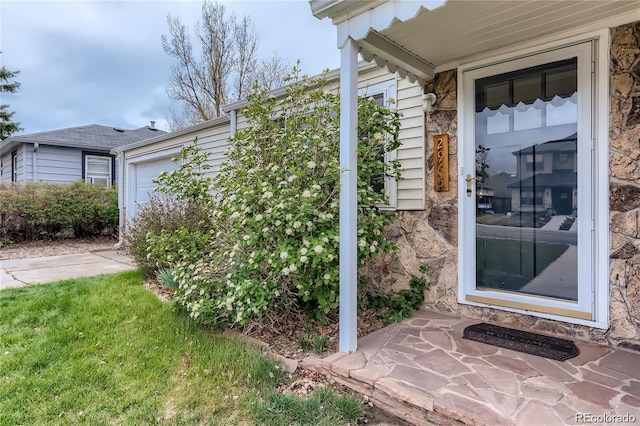 doorway to property with stone siding and a garage