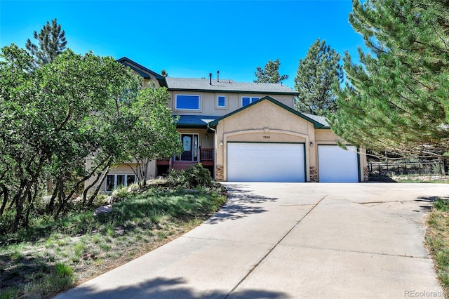 view of front facade with stucco siding, stone siding, a garage, and concrete driveway