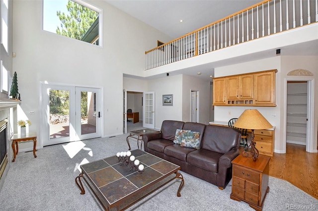 living room featuring a glass covered fireplace, french doors, baseboards, and a towering ceiling