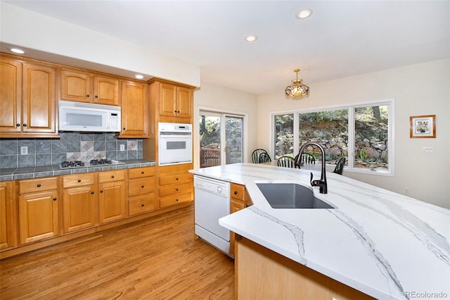 kitchen featuring plenty of natural light, backsplash, white appliances, and a sink