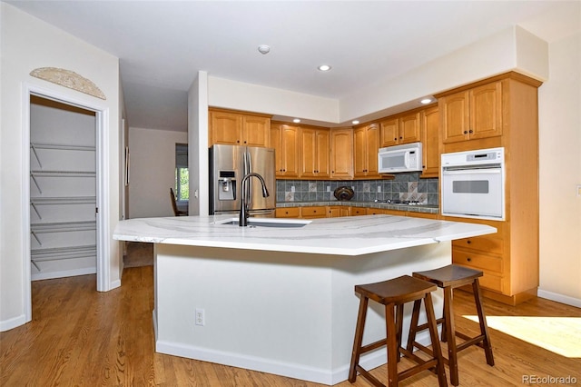 kitchen with a sink, decorative backsplash, light stone counters, and appliances with stainless steel finishes