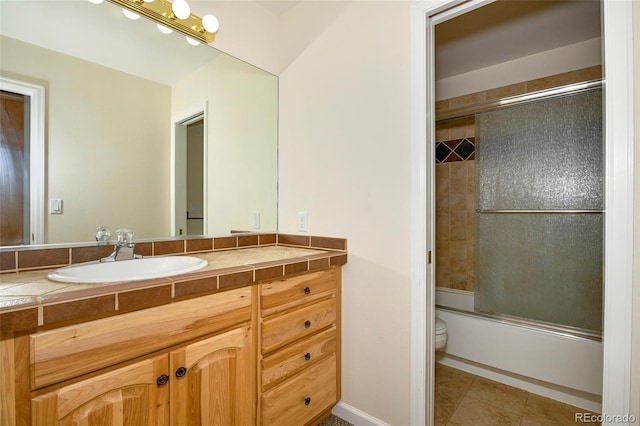 bathroom with vanity, tile patterned floors, toilet, and bath / shower combo with glass door