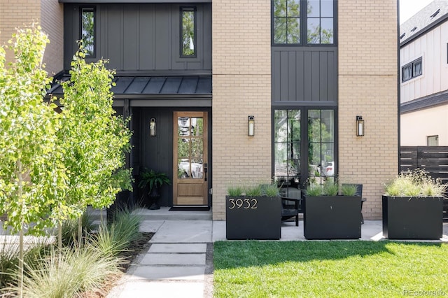 3932 Kalamath St, Denver, CO 80211 - view of exterior entry with board and batten siding, brick siding, a standing seam roof, and a lawn