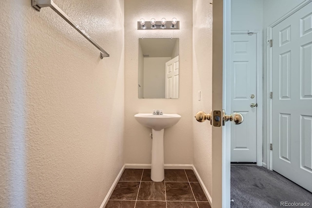 bathroom with a textured wall and baseboards