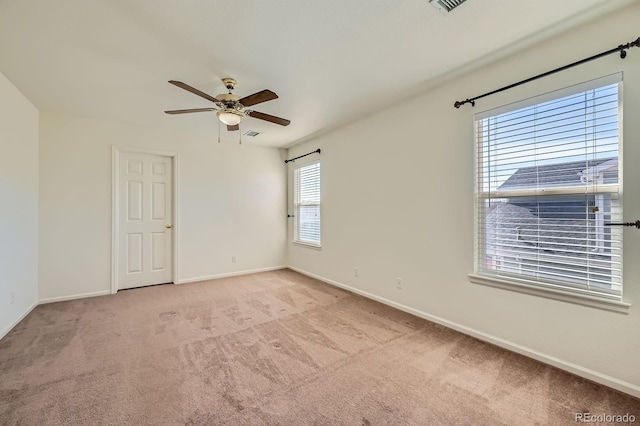 carpeted empty room with a ceiling fan and baseboards