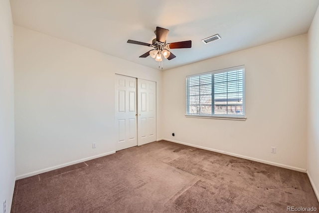 unfurnished bedroom featuring a ceiling fan, carpet, visible vents, baseboards, and a closet