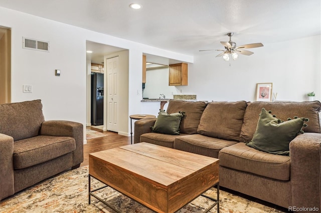 living room with ceiling fan and light hardwood / wood-style flooring