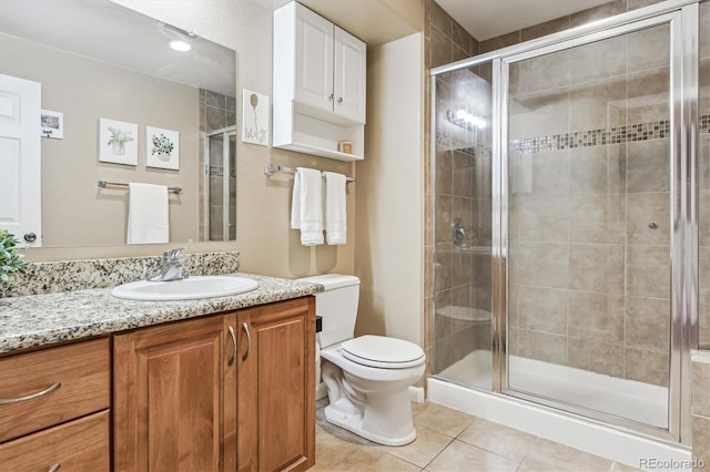 bathroom with vanity, toilet, a shower with shower door, and tile patterned flooring