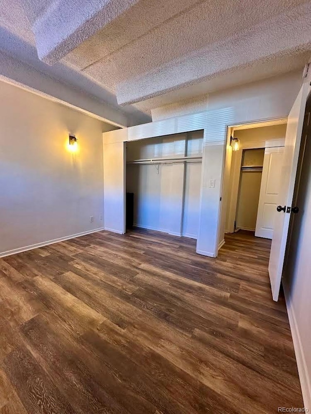 unfurnished bedroom featuring a closet, dark hardwood / wood-style flooring, and a textured ceiling