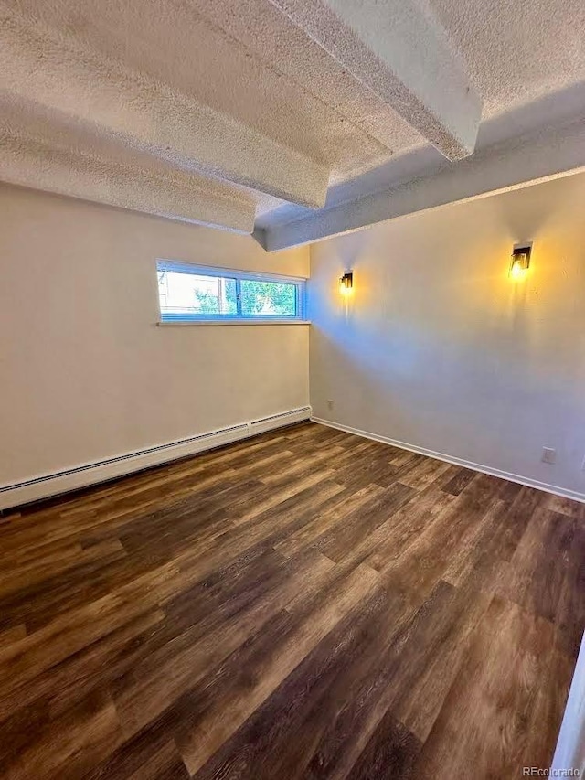 basement with dark hardwood / wood-style floors, a textured ceiling, and a baseboard heating unit