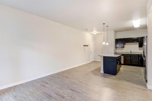 kitchen with light wood-type flooring, sink, pendant lighting, a center island, and stainless steel refrigerator