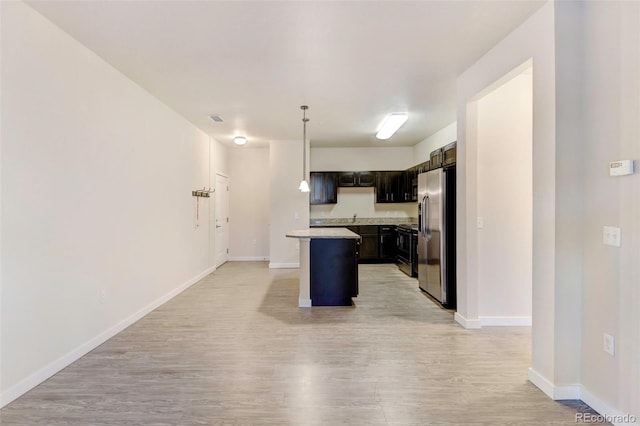 kitchen with stainless steel fridge, light wood-type flooring, dark brown cabinetry, decorative light fixtures, and a kitchen island