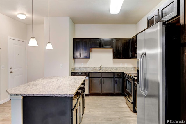 kitchen featuring sink, light wood-type flooring, decorative light fixtures, and appliances with stainless steel finishes