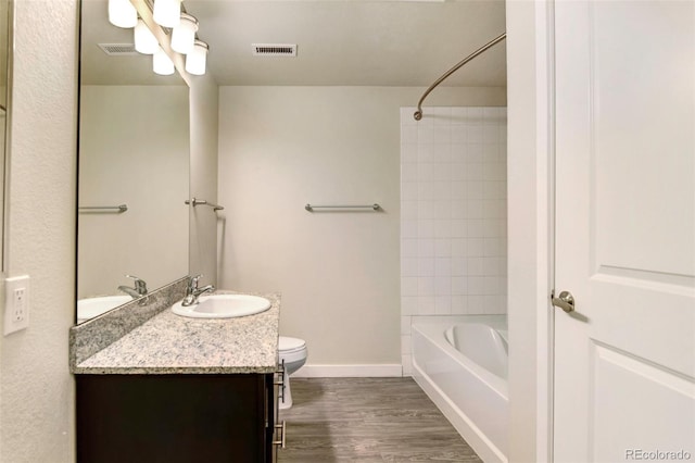 full bathroom featuring wood-type flooring, vanity, toilet, and tiled shower / bath combo