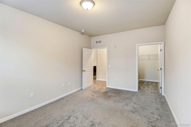 unfurnished bedroom with light colored carpet, a spacious closet, and a closet