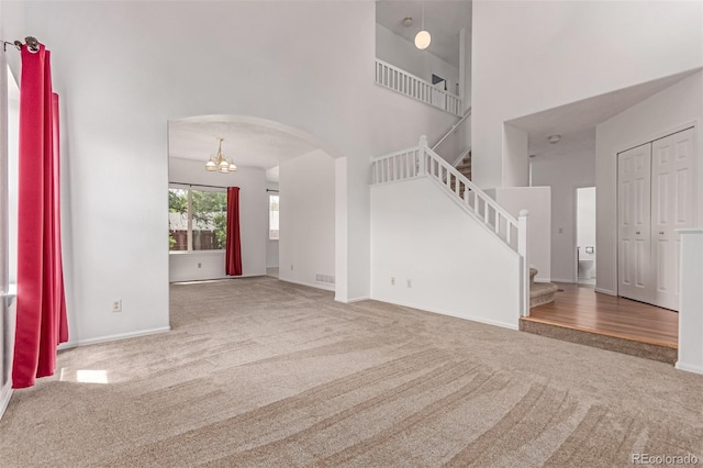 12825 Forest Way, Thornton, CO 80241 - unfurnished living room with carpet floors, a high ceiling, stairs, arched walkways, and a chandelier