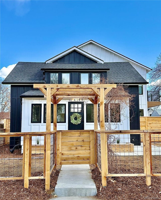 view of front of property featuring a fenced front yard, central AC, board and batten siding, and roof with shingles