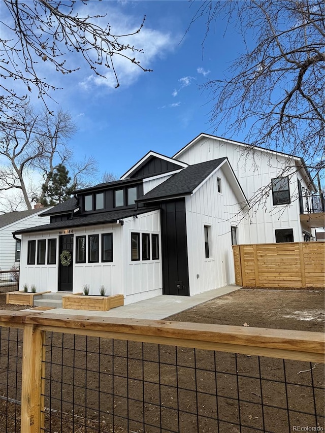 modern inspired farmhouse with fence, board and batten siding, and roof with shingles