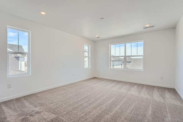 carpeted empty room featuring recessed lighting, visible vents, and baseboards