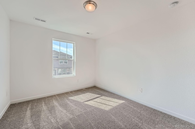 carpeted spare room with visible vents and baseboards