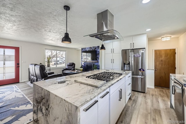 kitchen with light stone countertops, light wood-style flooring, island exhaust hood, and appliances with stainless steel finishes