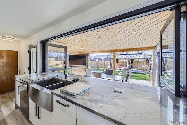 kitchen featuring white cabinets, dishwasher, wood ceiling, stone counters, and a sink