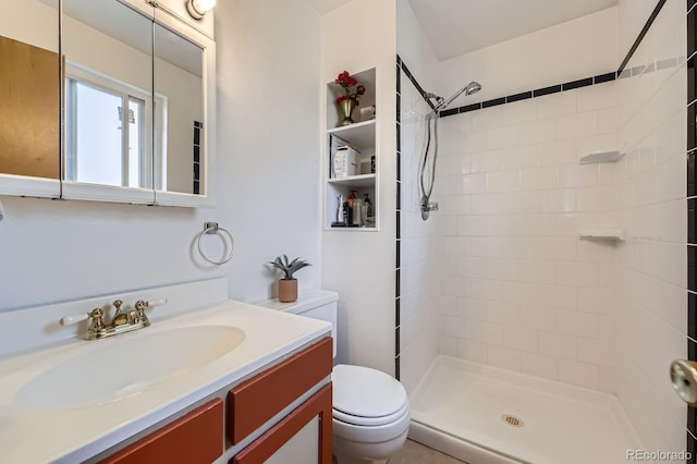 bathroom with tiled shower, vanity, and toilet