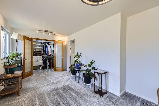 interior space with french doors, carpet, rail lighting, and baseboards