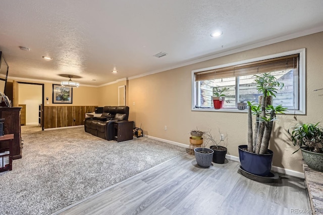 sitting room featuring ornamental molding, visible vents, a textured ceiling, and wood finished floors