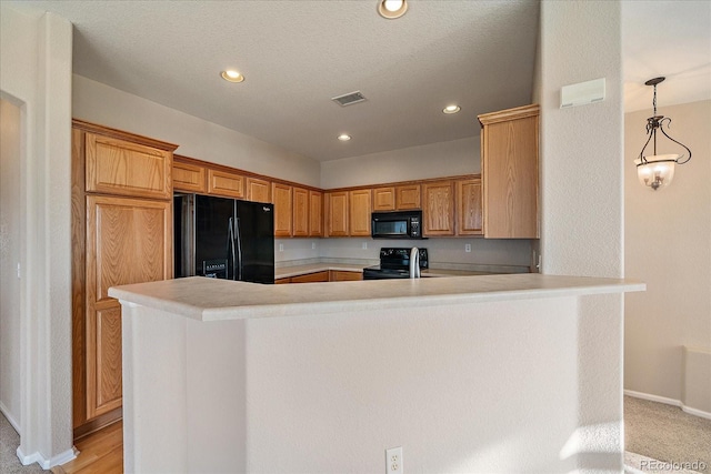 kitchen featuring black appliances, a peninsula, light countertops, baseboards, and visible vents