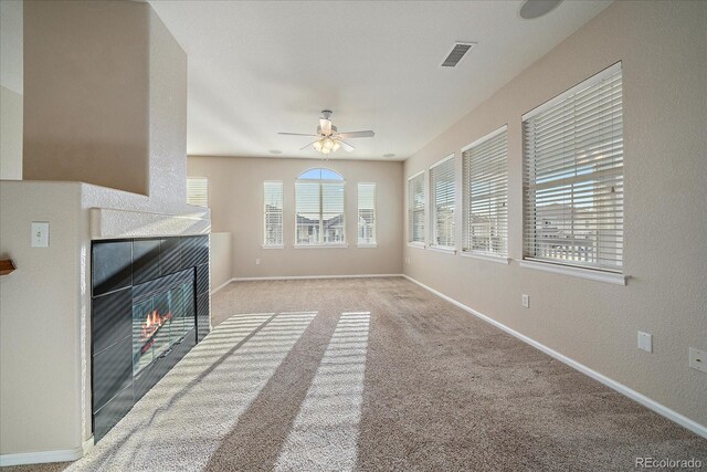 unfurnished living room with ceiling fan, baseboards, a tile fireplace, and visible vents
