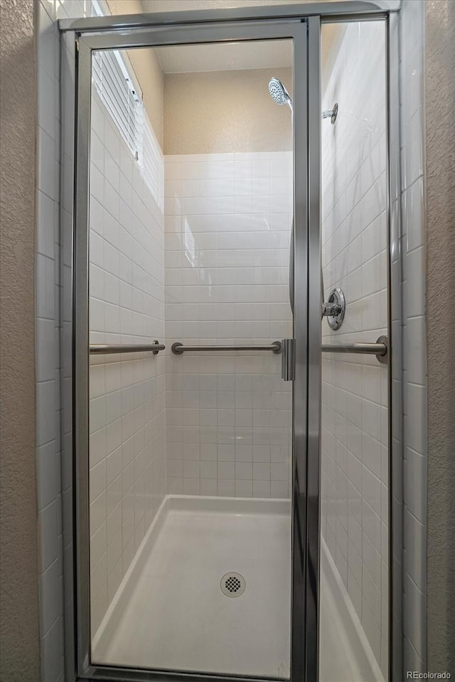 full bathroom with a textured wall and a stall shower