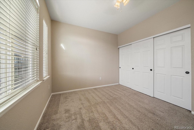 unfurnished bedroom featuring baseboards, multiple windows, and carpet
