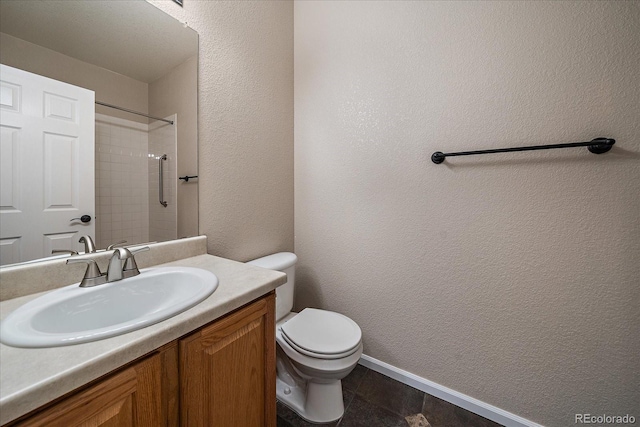 bathroom with a textured wall, toilet, vanity, baseboards, and a shower