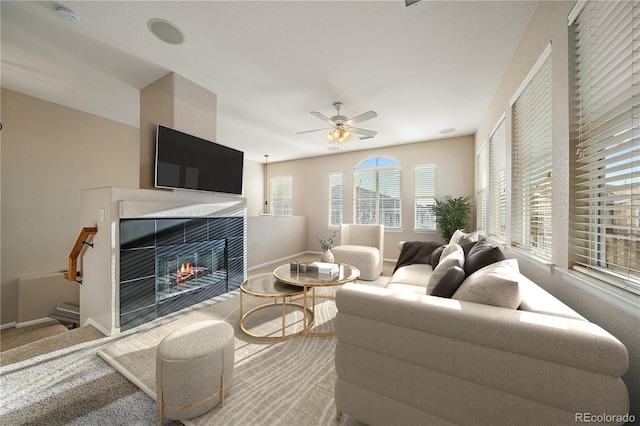 living area with a tile fireplace, carpet floors, baseboards, and ceiling fan