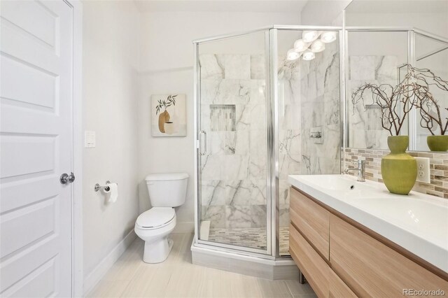 4603 W 33rd Ave, Denver, CO 80212 - full bathroom featuring toilet, double vanity, a marble finish shower, baseboards, and backsplash