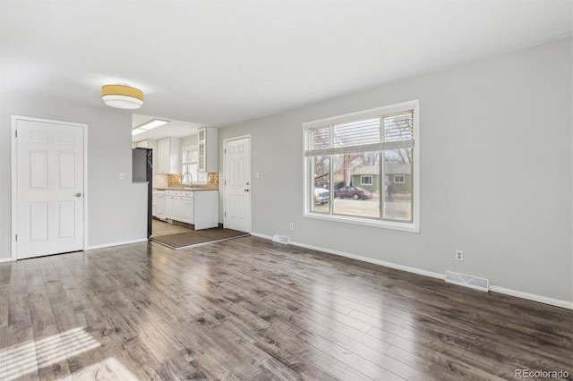 unfurnished living room featuring sink and dark wood-type flooring