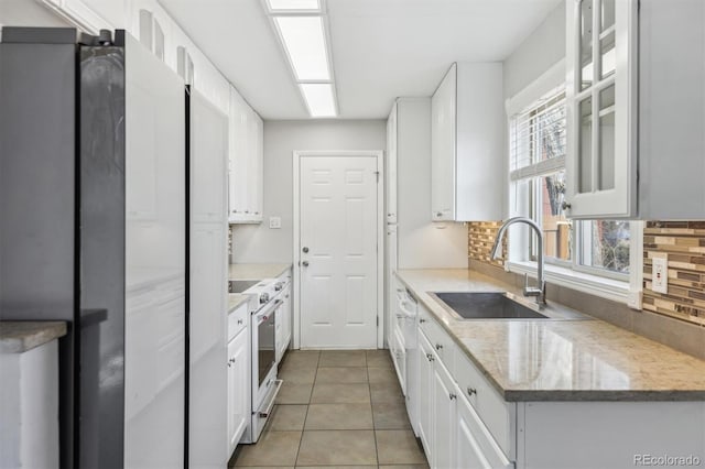 kitchen with high quality stove, sink, white cabinets, and backsplash