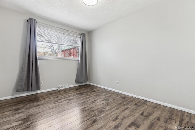 spare room featuring dark wood-type flooring and a textured ceiling