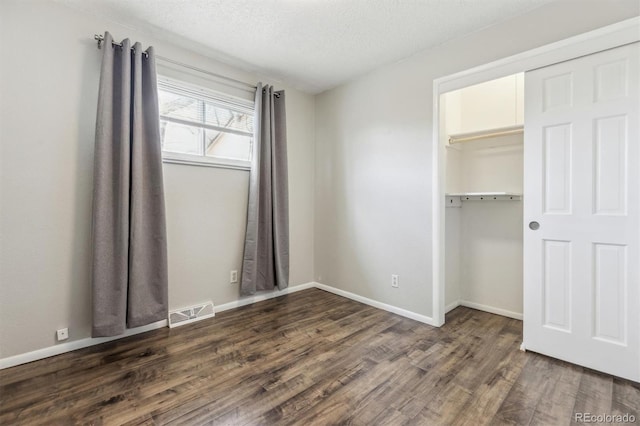 unfurnished bedroom featuring a textured ceiling, dark hardwood / wood-style flooring, and a closet